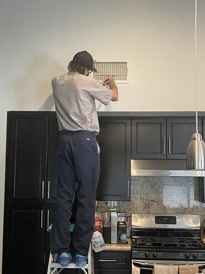 Technician inspecting an air vent during HVAC service in Aurora